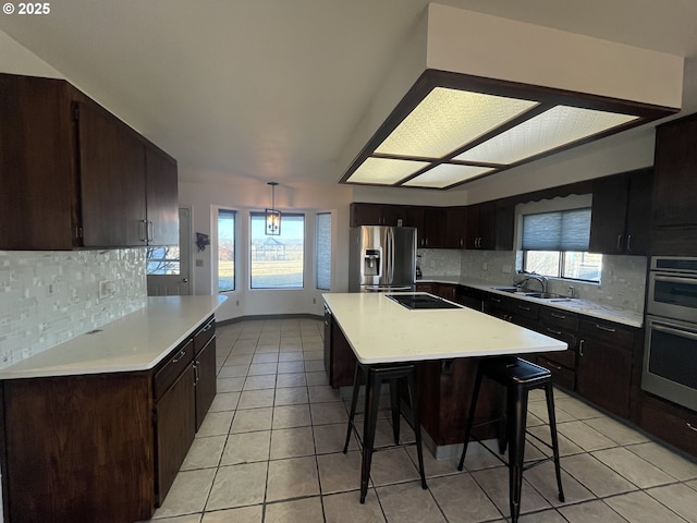 kitchen with backsplash, light countertops, appliances with stainless steel finishes, and a kitchen bar