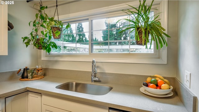 kitchen featuring white cabinetry, light countertops, and a sink