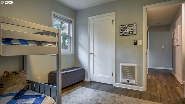 bedroom featuring baseboards, wood finished floors, and heating unit