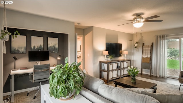 living room with ceiling fan, baseboards, and wood finished floors