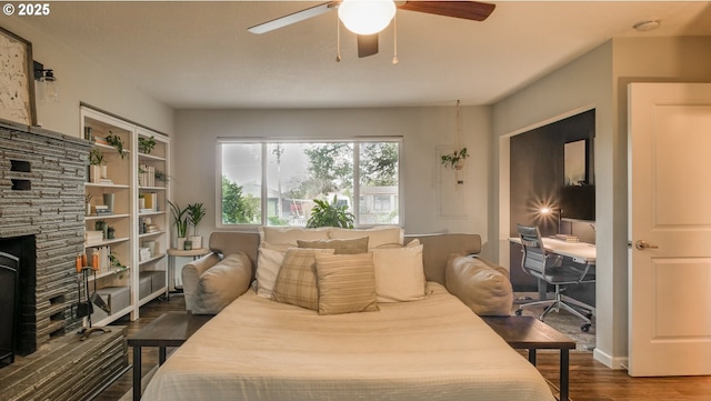 bedroom with ceiling fan, a fireplace, and wood finished floors