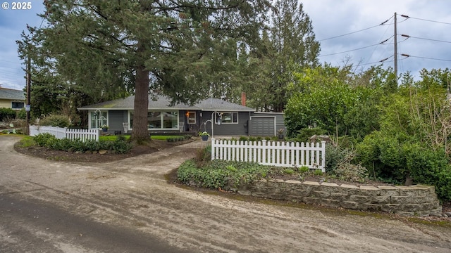 single story home with a fenced front yard, driveway, and a chimney