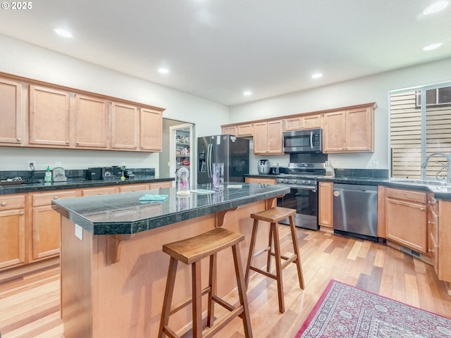 21390 SW Roellich Ave, Sherwood, OR 97140 - kitchen with appliances with stainless steel finishes, a sink, light wood-style flooring, a kitchen breakfast bar, and light brown cabinets