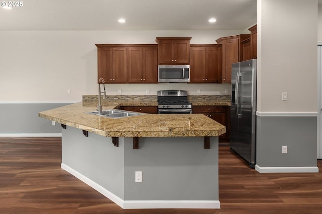 kitchen featuring a sink, dark wood-style floors, appliances with stainless steel finishes, a peninsula, and tile counters