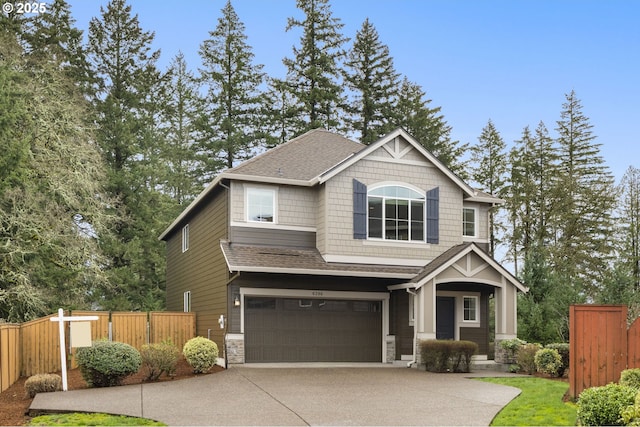 craftsman-style home with fence, roof with shingles, an attached garage, concrete driveway, and stone siding