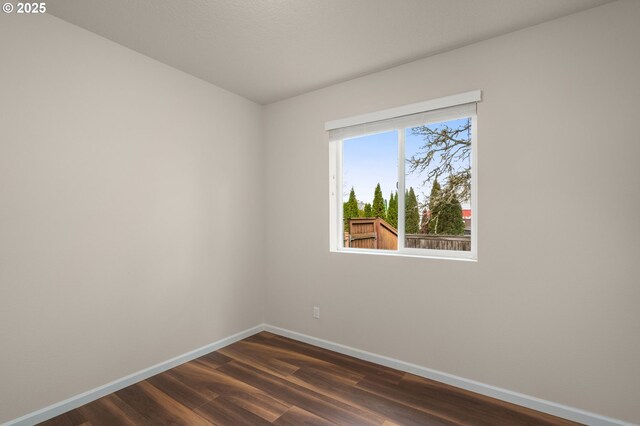 empty room featuring dark wood-style floors and baseboards