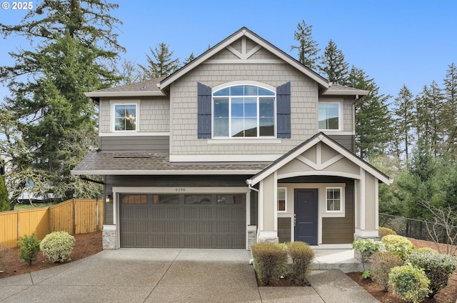 craftsman house featuring a garage, roof with shingles, concrete driveway, and fence