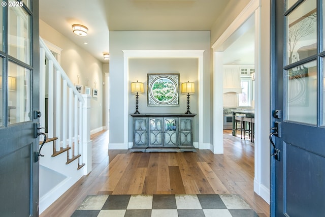 entryway with stairs, baseboards, and wood finished floors