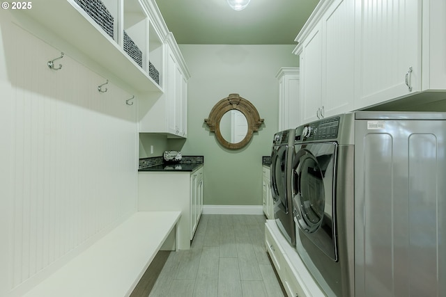laundry area with baseboards, separate washer and dryer, and cabinet space