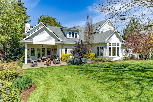 rear view of property with ceiling fan, a patio, a lawn, and an outdoor fire pit