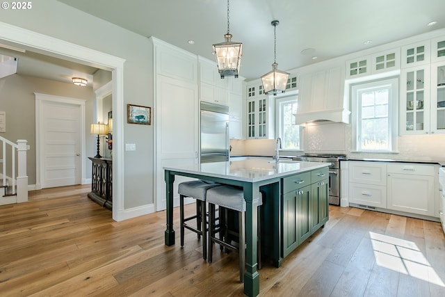 kitchen featuring premium appliances, light wood-style flooring, and white cabinetry