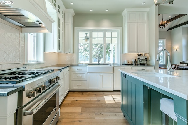 kitchen featuring white cabinetry, custom range hood, high end range, and a sink