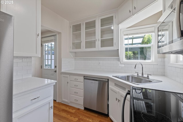 15234 SE Stark St, Portland, OR 97233 - kitchen featuring appliances with stainless steel finishes, white cabinets, decorative backsplash, and light countertops