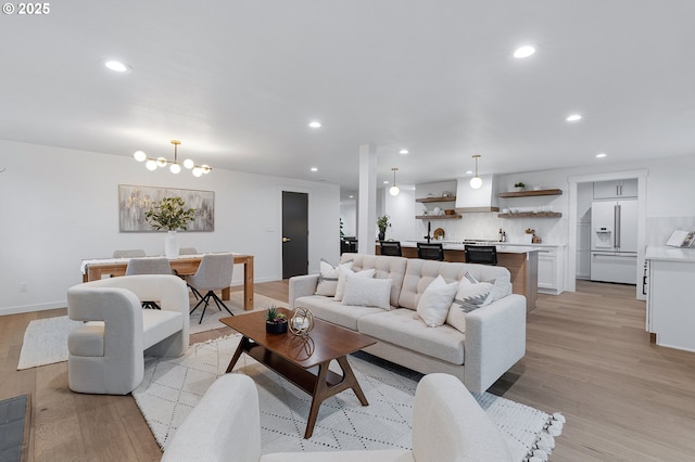 living room with a notable chandelier, recessed lighting, and light wood-style flooring