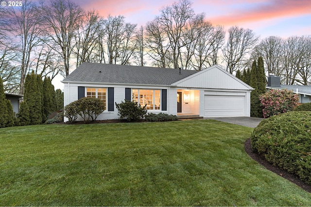 single story home featuring brick siding, roof with shingles, a yard, a garage, and driveway