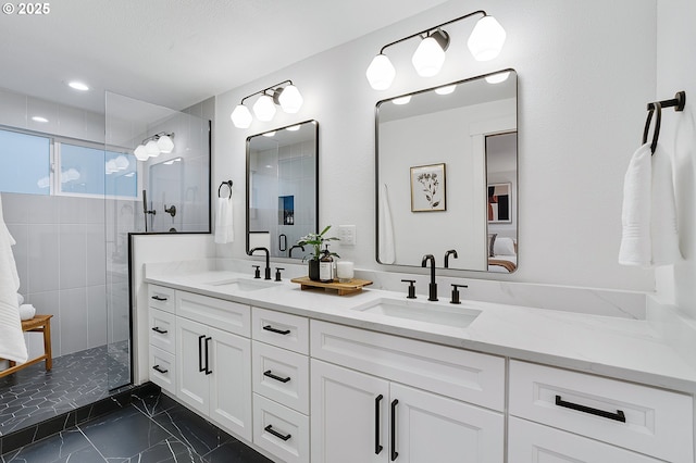 bathroom featuring double vanity, tiled shower, marble finish floor, and a sink