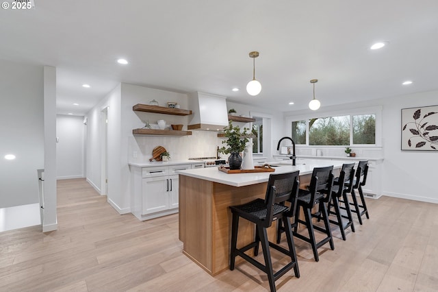 kitchen with premium range hood, open shelves, light wood-style floors, white cabinets, and light countertops