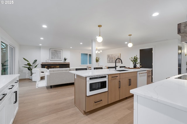 kitchen featuring a sink, light wood-type flooring, recessed lighting, and white dishwasher