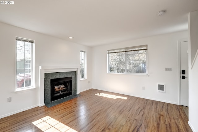 unfurnished living room with recessed lighting, baseboards, wood finished floors, and a tiled fireplace