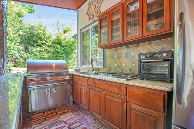 9459 SE Tarnahan Dr, Happy Valley, OR 97086 - kitchen featuring appliances with stainless steel finishes, tasteful backsplash, brick flooring, a sink, and glass insert cabinets