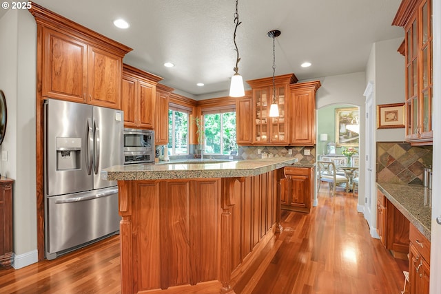 9459 SE Tarnahan Dr, Happy Valley, OR 97086 - kitchen featuring stainless steel appliances, wood finished floors, brown cabinetry, decorative backsplash, and recessed lighting