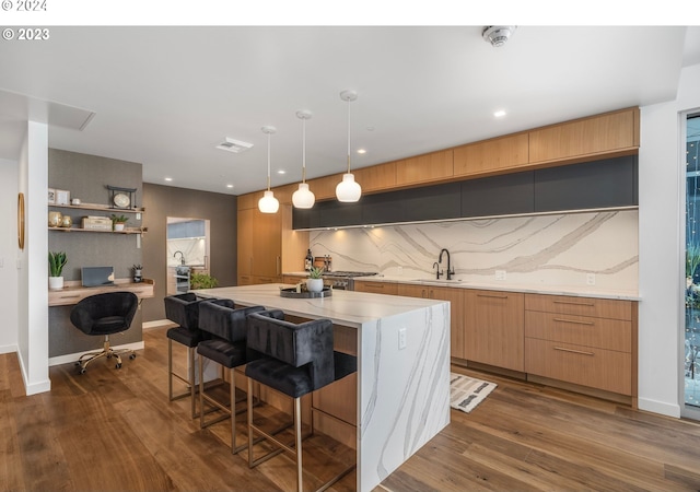 kitchen featuring a breakfast bar, a kitchen island, dark wood-type flooring, and a sink