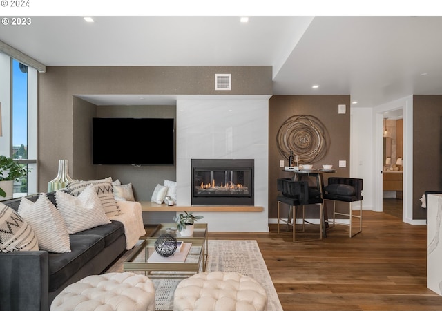 living area featuring visible vents, wood finished floors, recessed lighting, a large fireplace, and baseboards