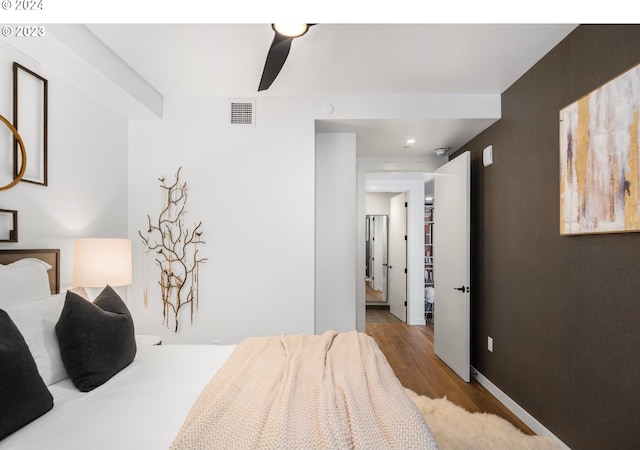 bedroom with wood finished floors, visible vents, and baseboards