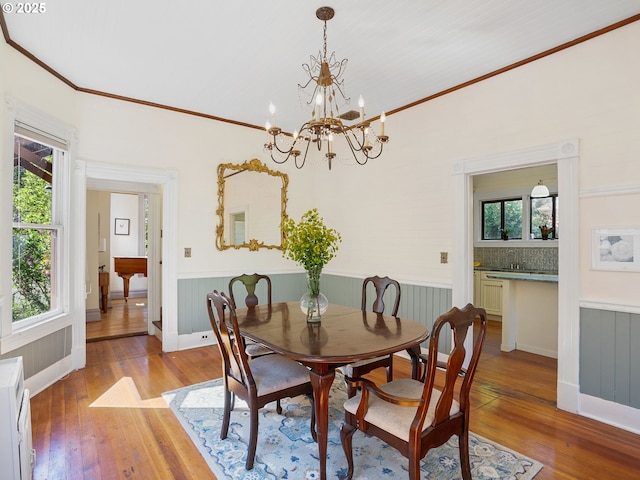 131 NE Tillamook St, Portland, OR 97212 - dining area with wainscoting, light wood-style floors, a chandelier, plenty of natural light, and crown molding