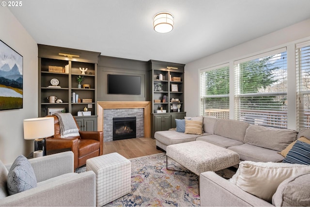 living room with light hardwood / wood-style floors, built in features, and a tile fireplace