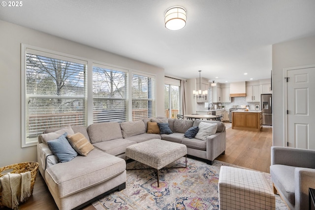 living room featuring a notable chandelier, sink, and light hardwood / wood-style flooring