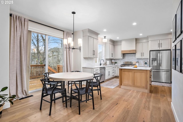 kitchen featuring custom range hood, stainless steel appliances, sink, a center island, and white cabinetry