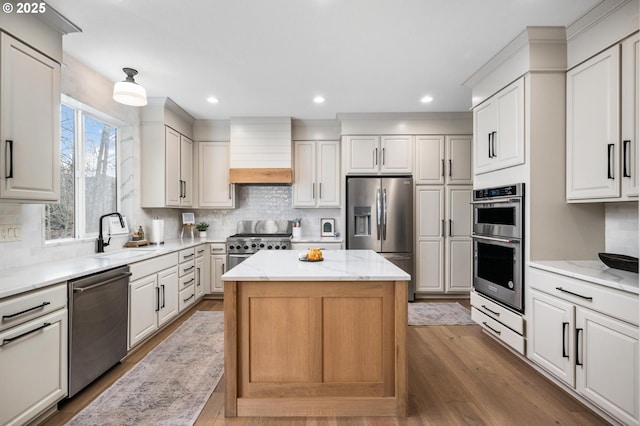 kitchen featuring hardwood / wood-style floors, a center island, premium range hood, sink, and stainless steel appliances