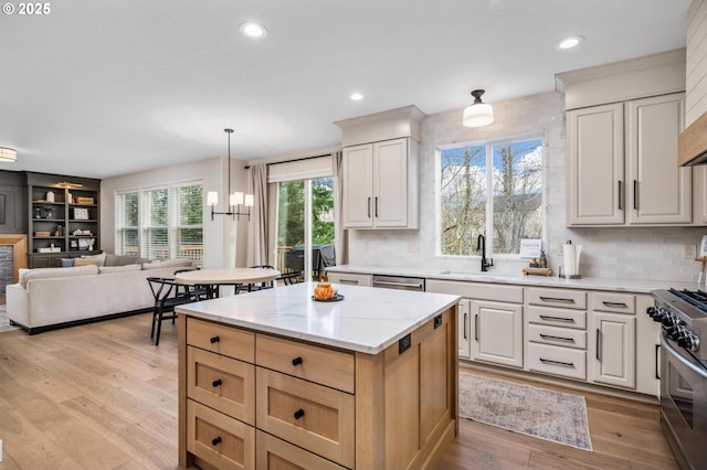 kitchen with appliances with stainless steel finishes, sink, pendant lighting, a center island, and white cabinetry