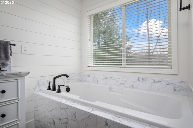 bathroom with tiled tub and vanity