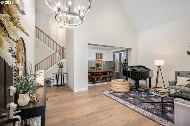 living room with high vaulted ceiling, light hardwood / wood-style floors, and an inviting chandelier