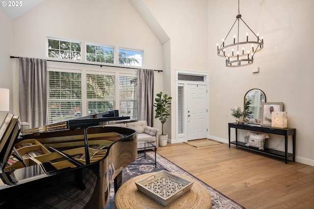 foyer entrance with high vaulted ceiling, wood-type flooring, and an inviting chandelier