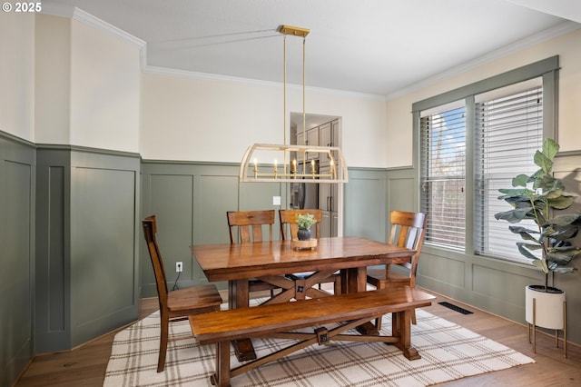 dining area featuring light hardwood / wood-style floors, crown molding, and an inviting chandelier