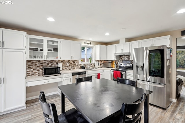 kitchen featuring white cabinetry, appliances with stainless steel finishes, light hardwood / wood-style floors, and decorative backsplash