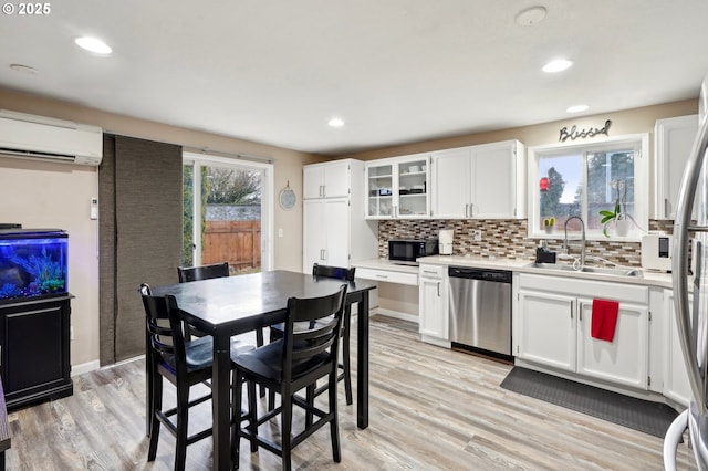 kitchen featuring appliances with stainless steel finishes, tasteful backsplash, white cabinetry, sink, and a wall unit AC