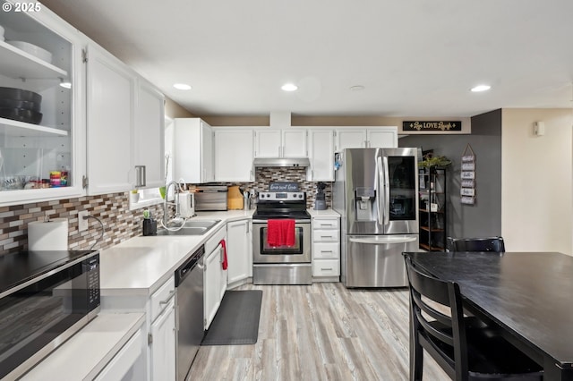 kitchen featuring stainless steel appliances, white cabinets, light wood-type flooring, and decorative backsplash