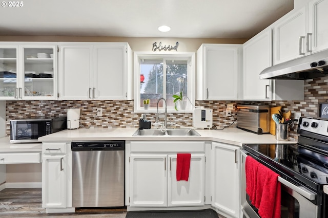 kitchen with tasteful backsplash, appliances with stainless steel finishes, sink, and white cabinets