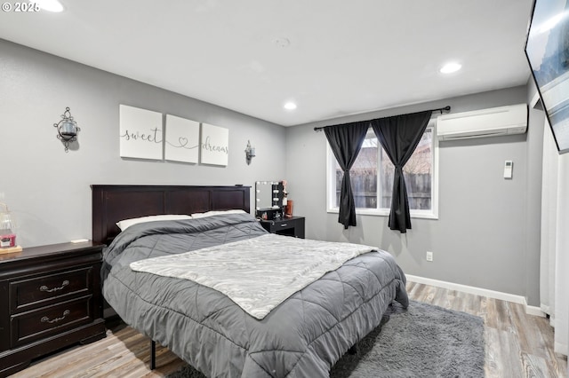 bedroom featuring light hardwood / wood-style flooring and a wall unit AC