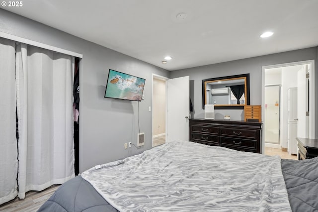 bedroom with a closet, ensuite bathroom, and light hardwood / wood-style flooring