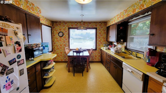 kitchen with white appliances, baseboards, wallpapered walls, a sink, and light countertops