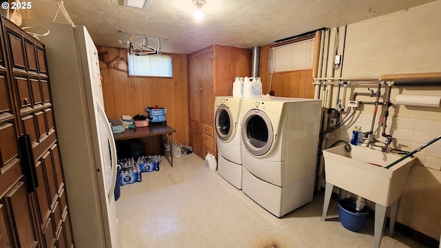 laundry room with wooden walls, light floors, laundry area, separate washer and dryer, and a textured ceiling