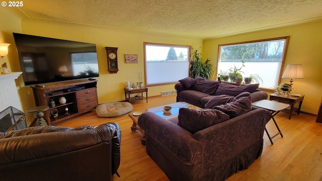 living area featuring baseboards, wood finished floors, visible vents, and a textured ceiling