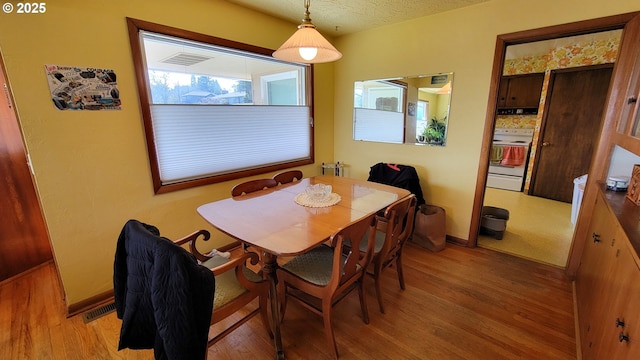 dining room with baseboards, wood finished floors, visible vents, and a textured ceiling