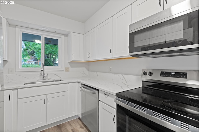 245 NE 4th Ave, Hillsboro, OR 97124 - kitchen with appliances with stainless steel finishes, a sink, light stone countertops, white cabinets, and light wood-style flooring
