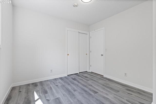 245 NE 4th Ave, Hillsboro, OR 97124 - unfurnished bedroom featuring wood finished floors, baseboards, a closet, and a textured ceiling